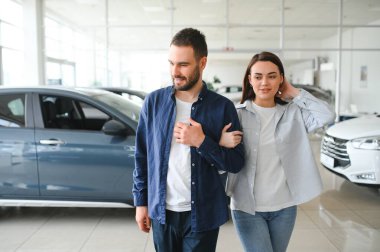 Galeriye başarılı bir ziyaret. Mutlu genç çift aile için yeni bir araba seçer ve alır..