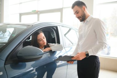 Yeni erkek mağaza asistanının direksiyonunda oturan mutlu, beyaz kadın müşteri kadın müşteri seçmesine yardım ediyor..