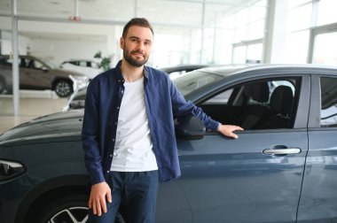 Gayri resmi kıyafet satan yakışıklı bir alıcı, arabanın yanında duran bir adam..