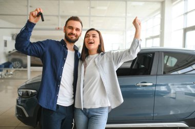Galeriye başarılı bir ziyaret. Mutlu genç çift aile için yeni bir araba seçer ve alır..
