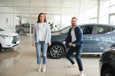 Galeriye başarılı bir ziyaret. Mutlu genç çift aile için yeni bir araba seçer ve alır..
