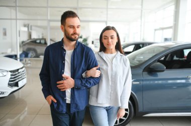 Mutlu genç çift aile için yeni bir araba seçer ve alır. Galeriyi ziyaret ediyorum..