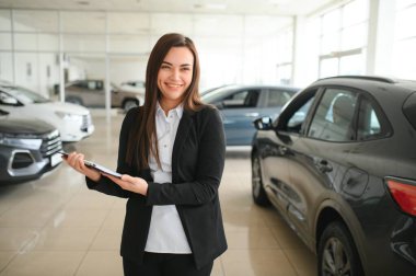 Gülümseyen satıcı kadın araba galerisinde belgeyi tutuyor..