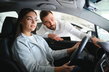 Yeni erkek mağaza asistanının direksiyonunda oturan mutlu, beyaz kadın müşteri kadın müşteri seçmesine yardım ediyor..