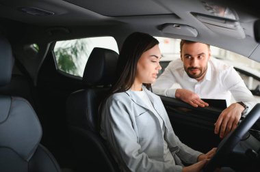 Yeni erkek mağaza asistanının direksiyonunda oturan mutlu, beyaz kadın müşteri kadın müşteri seçmesine yardım ediyor..