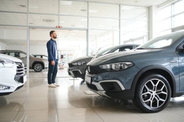 Genç adam yeni bir araç içinde araba Bayilik seçmektir.