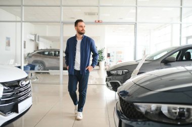 Gayri resmi kıyafet satan yakışıklı bir alıcı, arabanın yanında duran bir adam..