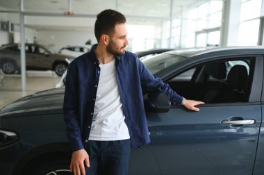 Genç adam yeni bir araç içinde araba Bayilik seçmektir.