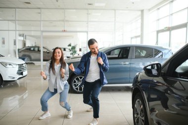 Mutlu genç çift aile için yeni bir araba seçer ve alır. Galeriyi ziyaret ediyorum..