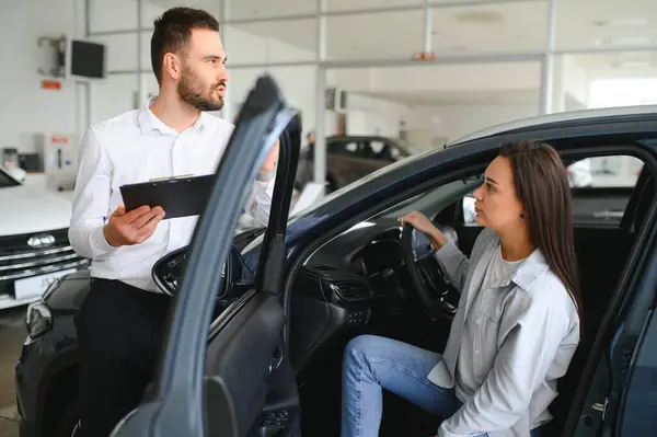 stock image Car seller showing customer brand new car and talking about its performances.