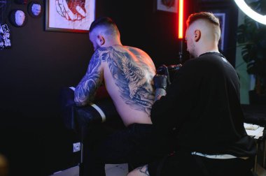 Dövme yaptırıyorum. Adam profesyonel bir dövme sanatçısı tarafından sırtında resim yaratıyor..