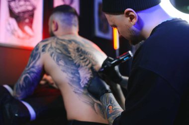 Dövme sanatçısı ve sırtında siyah mürekkeple dövmesi olan bir adam..