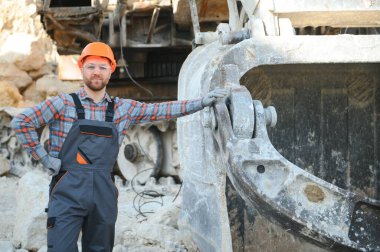 Taş ocağının arka planında duran bir işçinin portresi.