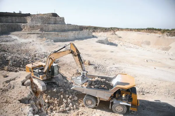 stock image Large quarry dump truck. Big yellow mining truck at work site. Loading stone into body truck.