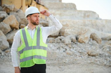 Taşın çıkarılması. Taş ocağının yanındaki erkek işçi. İnşaat alanında mühendis..