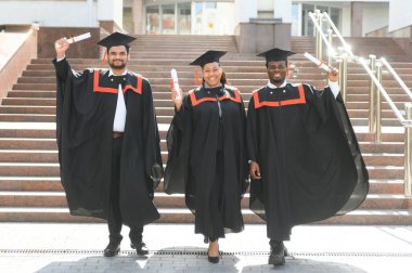 Üniversite kampüsünde diplomalı çeşitli uluslararası öğrenciler.