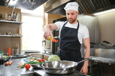 İşimi seviyorum Lokanta mutfağında duran neşeli genç şef.