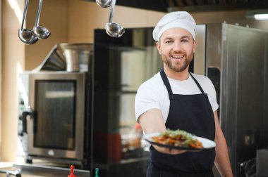 Yemek konsepti. Üniformalı genç bir şef restoranda yemek hazırlıyor..
