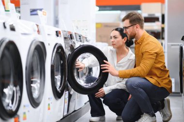 Elektronik mağazasında çamaşır makinesini seçen çift.