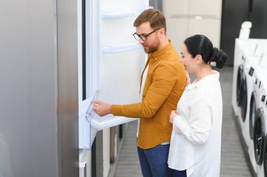 Çift, memnun müşteriler eşyalar mağazasında buzdolabı seçiyor..