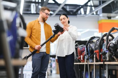 Genç ve güzel bir çift teknoloji mağazasından yeni elektrikli süpürge alıyor. Alışveriş yaparken eğleniyorum..