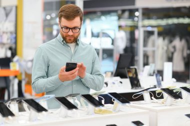 Mutlu adam cep telefonunu elektronik mağazasından seçiyor..