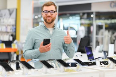 Elektronik mağazasındaki adam cep telefonunu seçiyor..