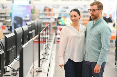 Genç çift ev aletleri, elektronik aletler ve aletler mağazasından plazma TV 'yi seçiyor. Yeni bir televizyon, indirim günü..