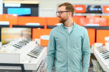 Bir adam bir elektronik mağazasında cep telefonlarının yanında duruyor.