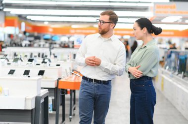 Perakende Ev Elektronik Uzmanından Tavsiye İsteyen Bir Kadın Müşterinin Portresi.