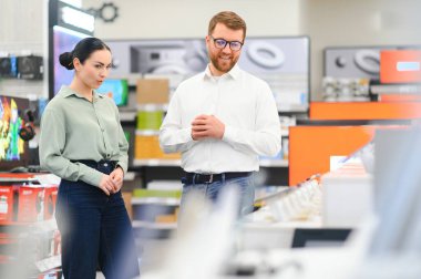 genç kadın tezgâhtar ev aletleri alışveriş merkezi süpermarket ile TV'nin seçimi.