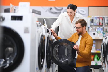 Elektronik mağazasında çamaşır makinesini seçen çift.