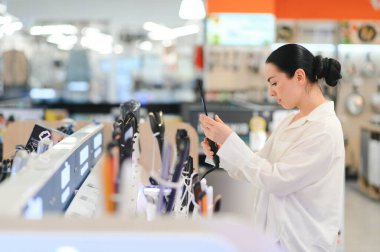 Kadın bir saç kurutma makinesi deposunda seçer..