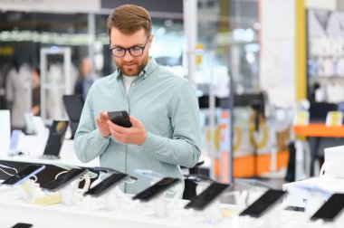 Elektronik mağazasındaki adam cep telefonunu seçiyor..