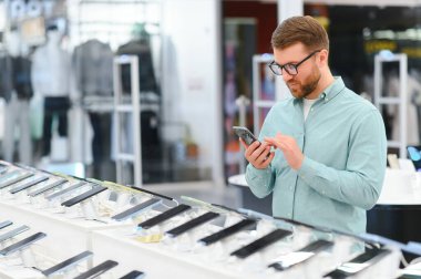 Elektronik mağazasındaki adam cep telefonunu seçiyor..