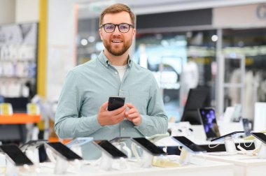 Mutlu adam cep telefonunu elektronik mağazasından seçiyor..