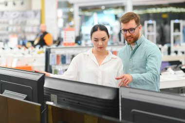 Genç çift ev aletleri, elektronik aletler ve aletler mağazasından plazma TV 'yi seçiyor. Yeni bir televizyon, indirim günü..