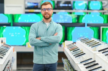 Bir adam bir elektronik mağazasında cep telefonlarının yanında duruyor.