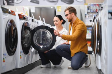 Elektronik mağazasında çamaşır makinesini seçen çift.
