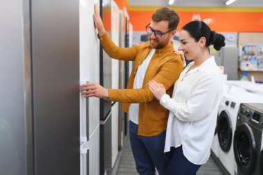 Çift, memnun müşteriler eşyalar mağazasında buzdolabı seçiyor..