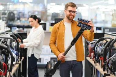 Genç ve güzel bir çift teknoloji mağazasından yeni elektrikli süpürge alıyor. Alışveriş yaparken eğleniyorum..