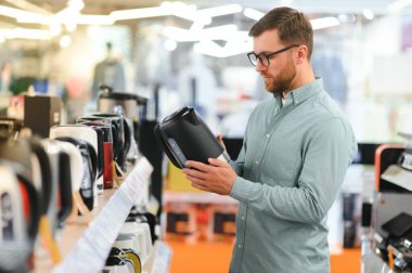 Akıllı genç müşteri süpermarkette çaydanlık seçiyor..