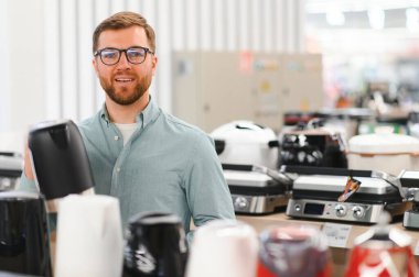 Akıllı genç müşteri süpermarkette çaydanlık seçiyor..