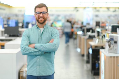 Bir adam bir elektronik mağazasında cep telefonlarının yanında duruyor.