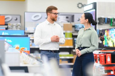 Perakende Ev Elektronik Uzmanından Tavsiye İsteyen Bir Kadın Müşterinin Portresi.