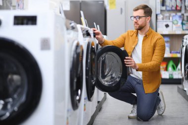 Adam galeride çamaşır makinesini seçiyor..