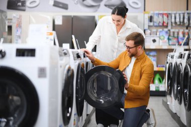 Elektronik mağazasında çamaşır makinesini seçen çift.