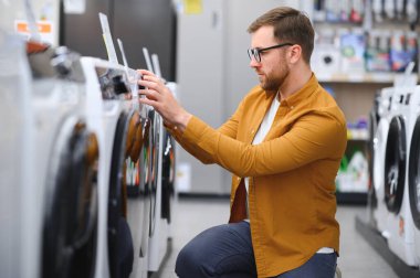 Adam galeride çamaşır makinesini seçiyor..