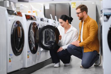 Elektronik mağazasında çamaşır makinesini seçen çift.
