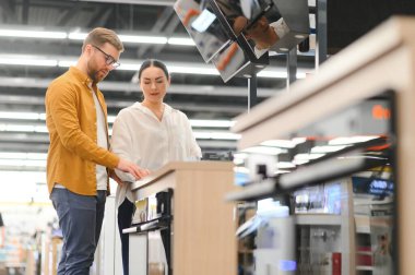 Genç bir çift süpermarketten yeni gaz sobası alıyor..